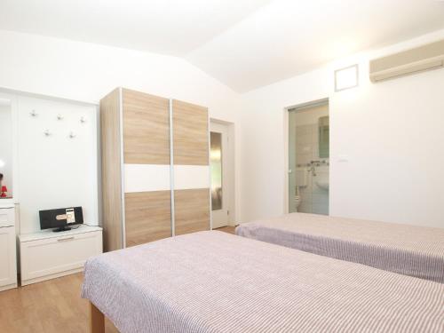 a white bedroom with two beds and a closet at House Mario 1931 in Banjole