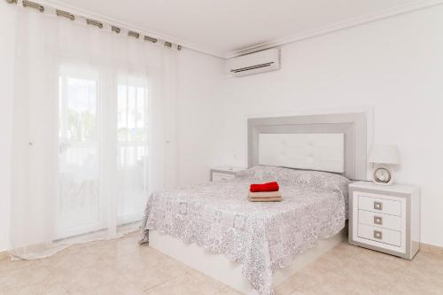 a white bedroom with a bed with a red hat on it at La Mata Bélgica in La Mata