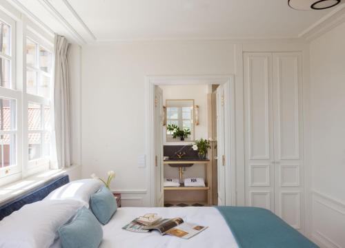 a white bedroom with a bed and a window at Gran hotel Brillante in San Esteban de Pravia