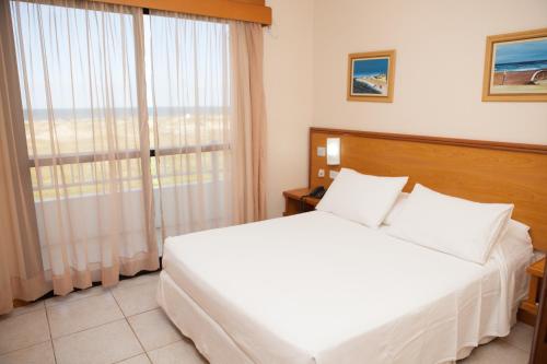 Un pat sau paturi într-o cameră la Nelson Praia Hotel