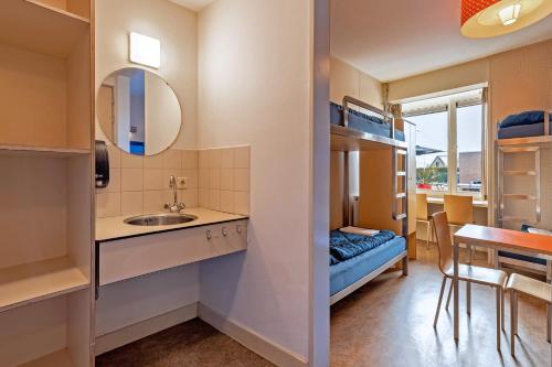 a small room with a sink and a bedroom at Stayokay Hostel Noordwijk in Noordwijk
