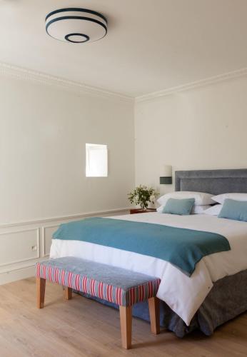 a white bedroom with a large bed and a bench at Gran hotel Brillante in San Esteban de Pravia