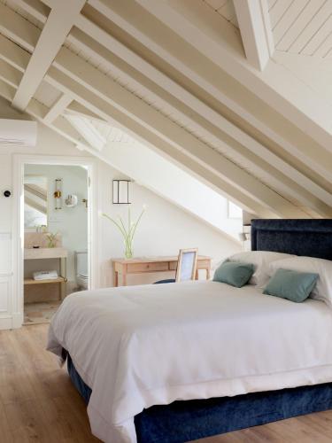 a bedroom with a large white bed with blue accents at Gran hotel Brillante in San Esteban de Pravia