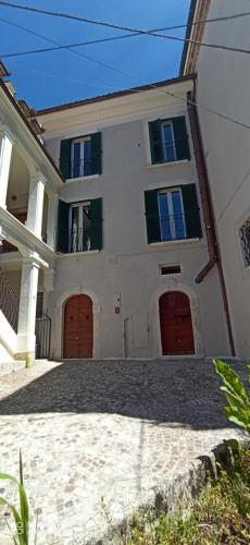 a large white house with brown garage doors at B&B Il Cardinale in Rocca di Mezzo