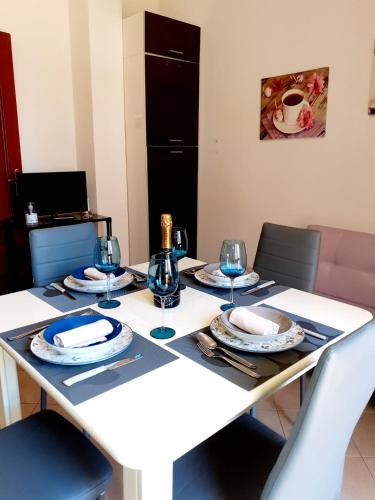 a white table with plates and wine glasses on it at Clizia Apartment in Alghero