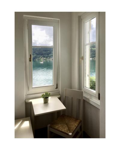 a table and a chair in a room with two windows at Villa Streintz in Millstatt