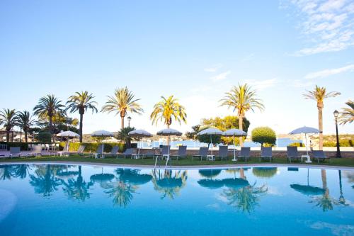 a swimming pool with chairs and umbrellas and palm trees at Seth Port Mahón in Mahón