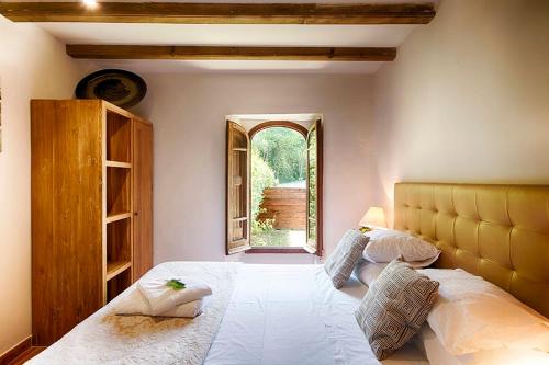 a bedroom with a large white bed with a window at Can Cruanyes in Sales del Llierca