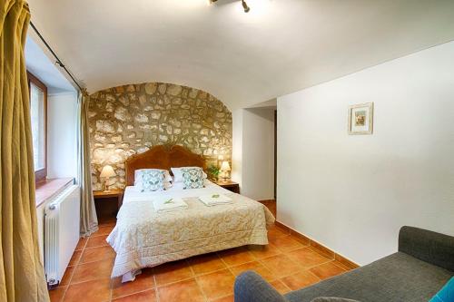 a bedroom with a bed and a stone wall at Can Cruanyes in Sales del Llierca