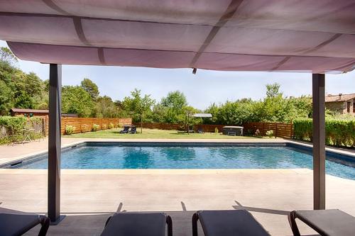 a swimming pool with an umbrella and chairs at Can Cruanyes in Sales del Llierca