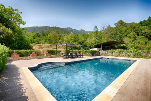 a swimming pool with two people sitting on chairs next to it at Can Cruanyes in Sales del Llierca