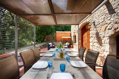 a long table with chairs and glasses on a patio at Can Cruanyes in Sales del Llierca