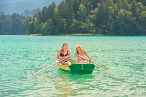 two women in a row boat on a lake at Gästehaus Trink B&B in Drobollach am Faakersee