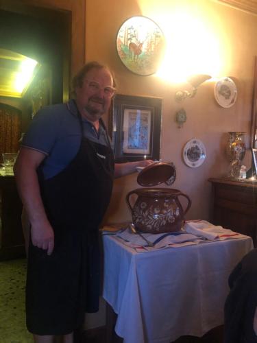 a man is standing next to a table with a vase at La Maison de juliette in Saint-Hippolyte