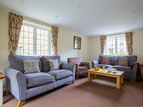 a living room with two blue couches and a table at Emma Dent in Winchcombe
