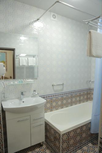 a bathroom with a tub and a sink and a bath tub at AL-MALIK Boutique Hotel in Bukhara