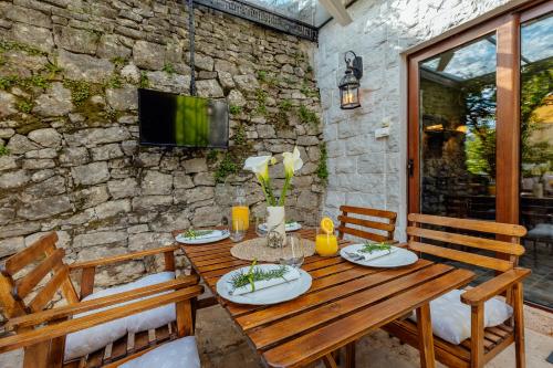 a wooden table with chairs and a tv on a stone wall at Apartman Glicinija in Herceg-Novi