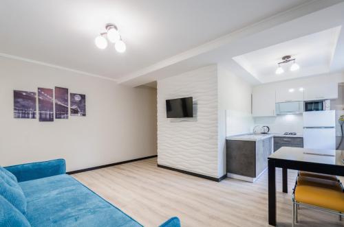 uma sala de estar com um sofá azul e uma cozinha em ARTAL Apartment on Obolonsky avenue 16 em Kiev