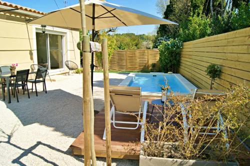 - une terrasse avec une table et un parasol à côté de la piscine dans l'établissement La Petite Maison en Provence, à Saint-Rémy-de-Provence