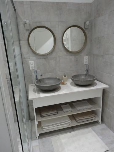 a bathroom with two sinks and two mirrors at Les Petites Tuileries in Bray-sur-Seine