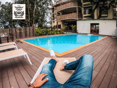 a woman laying on a chaise lounge next to a swimming pool at The Summer House, Pachmarhi - AM Hotel Kollection in Pachmarhī