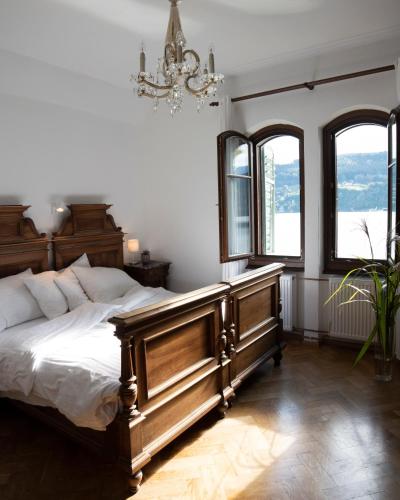 a bedroom with a wooden bed and two windows at Villa Streintz in Millstatt