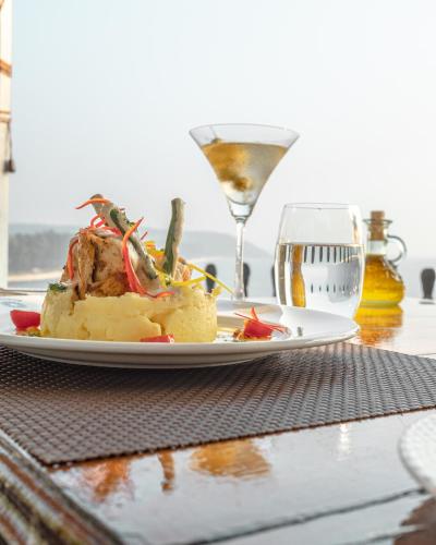 a plate of food on a table with a glass of wine at Fort Tiracol Goa in Arambol