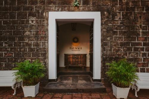a hallway with two potted plants in front of a brick wall at Fort Tiracol Goa in Arambol