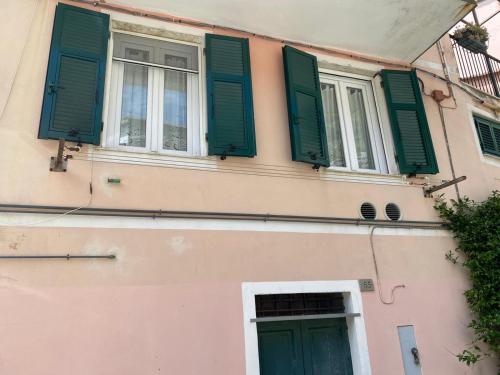 a pink building with green shutters and a window at Camere Nicolina 4 in Vernazza