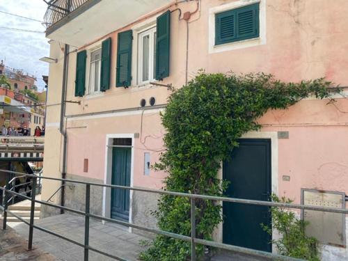 a pink building with green doors and a fence at Camere Nicolina 4 in Vernazza