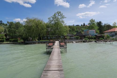 a wooden pier with benches in the water at Gránit Villa in Balatonszárszó