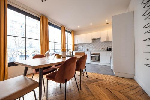 une cuisine et une salle à manger avec une table et des chaises en bois dans l'établissement MBM - Center of paris, à Paris