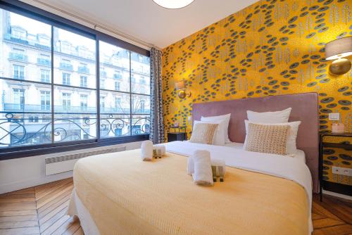 une chambre avec un grand lit et une grande fenêtre dans l'établissement MBM - Center of paris, à Paris