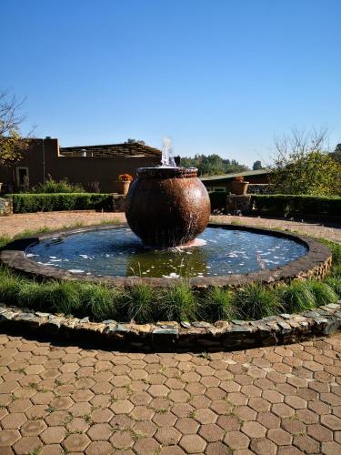 a large vase sitting in a fountain in a park at Riverstone Lodge in Muldersdrift
