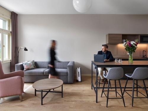 a man sitting at a table with a laptop in a living room at Franz BY ZEITRAUM in Prague