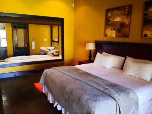 a bedroom with a bed and a tub in a bathroom at Riverstone Lodge in Muldersdrift