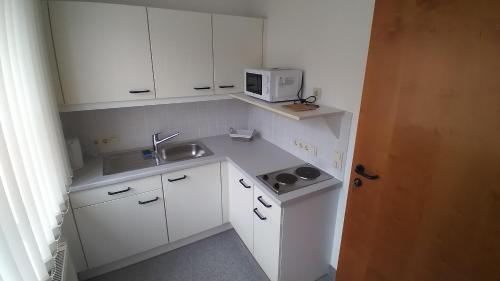 a small white kitchen with a sink and a microwave at Apartment Auszeit in Kirchberg an der Pielach