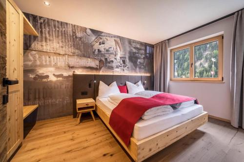 1 dormitorio con 1 cama y una pintura en la pared en Seebrunn - Kuppelwieser Alm, en Ultimo