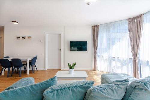 a living room with blue couches and a table at Elija Swan-Toy Apartments in Šventoji