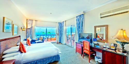 エル・アラメインにあるPorto Marina Resort & Spa Al Alameinのベッドと机、テレビが備わったホテルの部屋