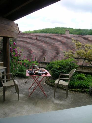 a patio with a table and two chairs and a brick wall at La Grange aux Roses in Tursac