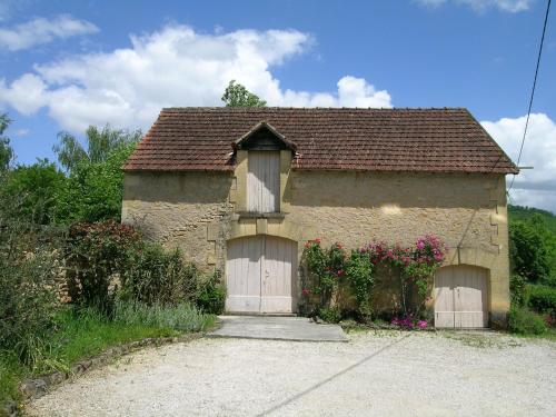 a small house with two garage doors and flowers at La Grange aux Roses in Tursac