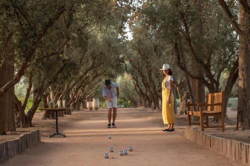 a man and a woman walking down a path with birds at The Oberoi Marrakech in Marrakech