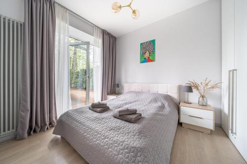 a white bedroom with a bed and a large window at Brand new apartment with terrace near the sea in Jūrmala
