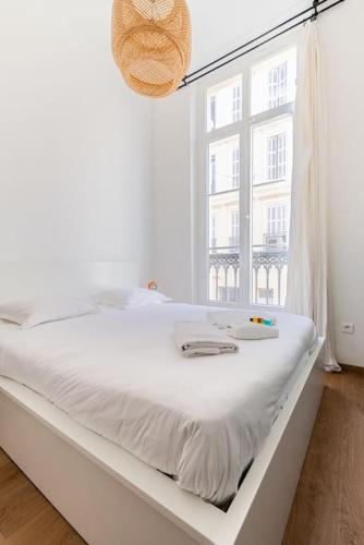un lit blanc dans une chambre avec une fenêtre dans l'établissement L'Occitane - Idéalement situé et entièrement rénové, à Marseille
