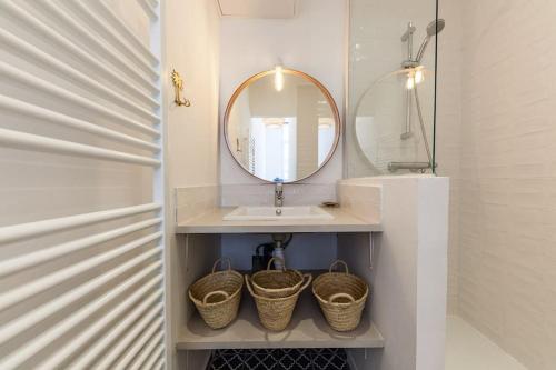 La salle de bains est pourvue d'un lavabo, d'un miroir et de paniers. dans l'établissement L'Occitane - Idéalement situé et entièrement rénové, à Marseille