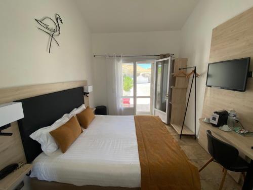 a bedroom with a bed and a desk and a television at Le Mas de Cocagne in Saintes-Maries-de-la-Mer