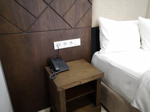 a telephone on a table next to a bed at East Palace Hotel in Almaty