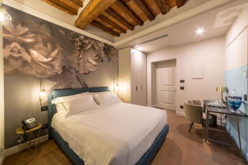 una camera con un grande letto e una scrivania con una scrivania di Palazzo 42 - Boutique Hotel & Suites a Pistoia