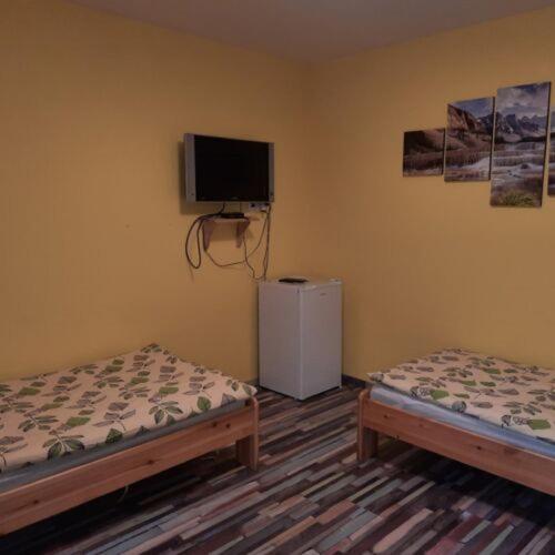 a room with two beds and a tv on the wall at Sanyi Vendégház in Dávod